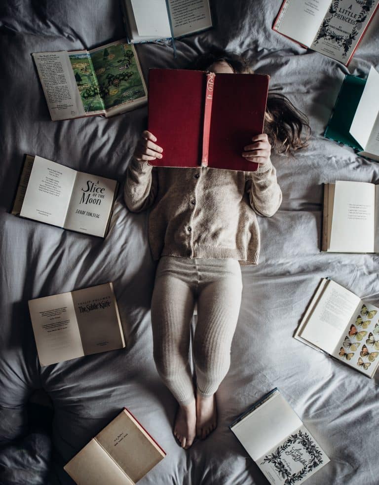 enfant entourée de livres et qui lit de annie-spratt